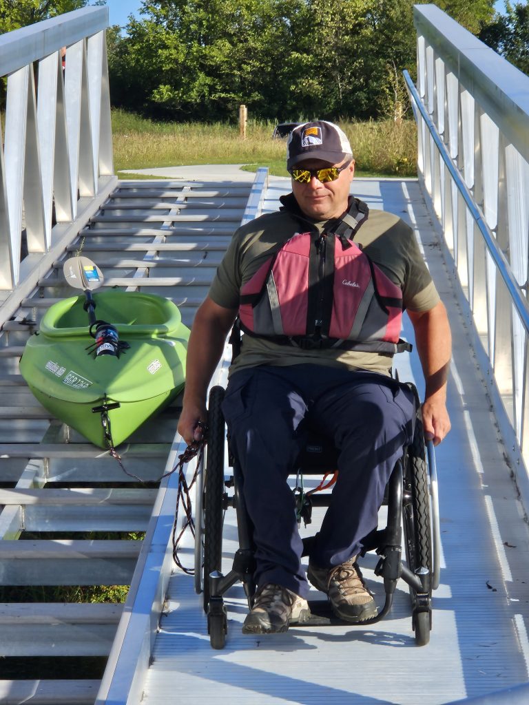 Adaptive recreationalist Bill Bogdan of Mokena tests out the new kayak/canoe launch at Lake Chaminwood Preserve near Channahon. The accessible device was installed recently by the Forest Preserve District of Will County to help people of all abilities enter and exit the water independently. –Photo by Forest Preserve staff, Cindy Cain and Chad Merda. YouTube Video Link: https://youtu.be/uKkr_plFP18?si=5LltNt1TdlrXn4H3