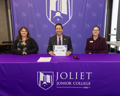 Joliet Junior College President Clyne Namuo (center) shows the agreement with college officials Diane Urbanczyk and Stephanie Braun. –Photo by Russell Bailey.