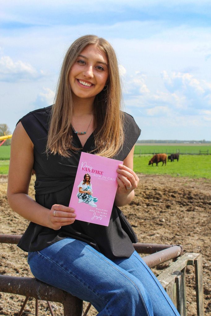 Paris Van Dyke shows off her new book at her grandparents’ farm. –Photo by Rhiannon Branch of FarmWeek.