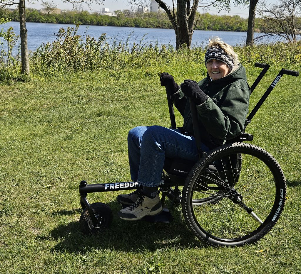 Kim Kosmatka, of Mokena, is the first person to test the new GRIT Freedom Chair at the Forest Preserve District of Will County’s Four Rivers Environmental Education Center in Channahon. She said she loved she could travel over grass, roots, and mud and feel secure while doing so. The wheelchair is available for public use at no cost. –Forest Preserve photo by Cindy Cain.