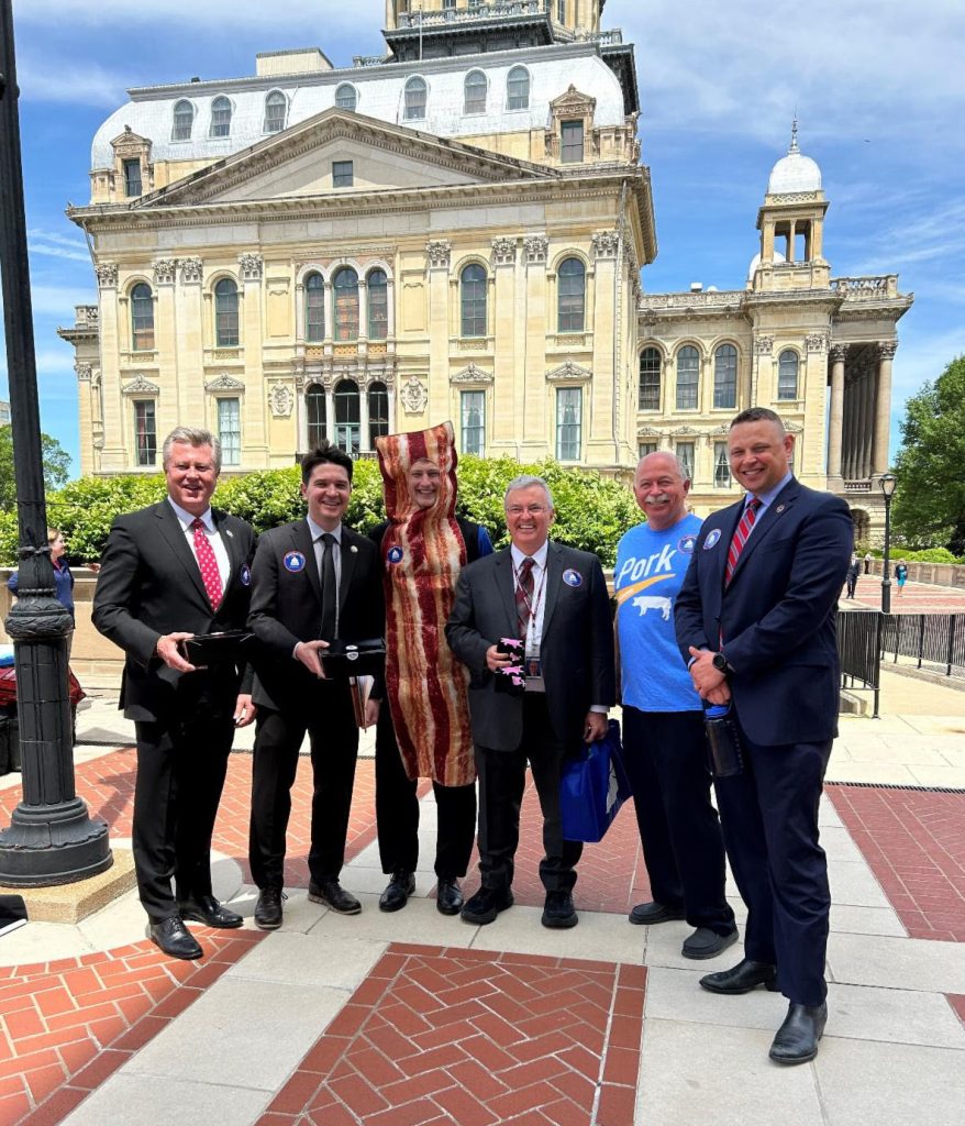 Sen. Seth Lewis, Sen. Steve McClure, FFA Officer Thaddeus Bergschneider, Sen. Tom Bennett, IPPA At-Large Director Bruce Brinkman, and Sen. Neil Anderson pose for a quick picture during Illinois Bacon Day festivities. –Photo submitted.
